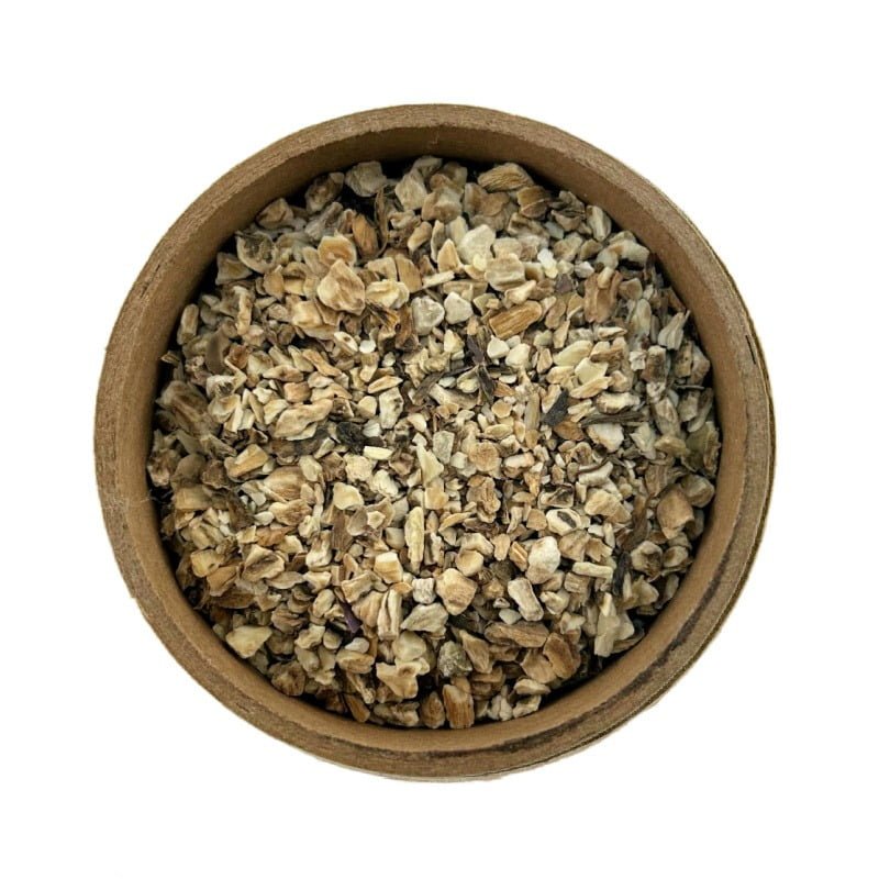 A close-up view of a circular bowl filled with loose, dried herbal tea blend, isolated on a white background.