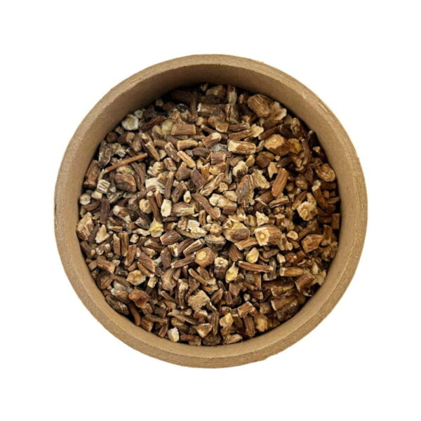 A top view of a round container filled with various chopped and dried roots or herbs.